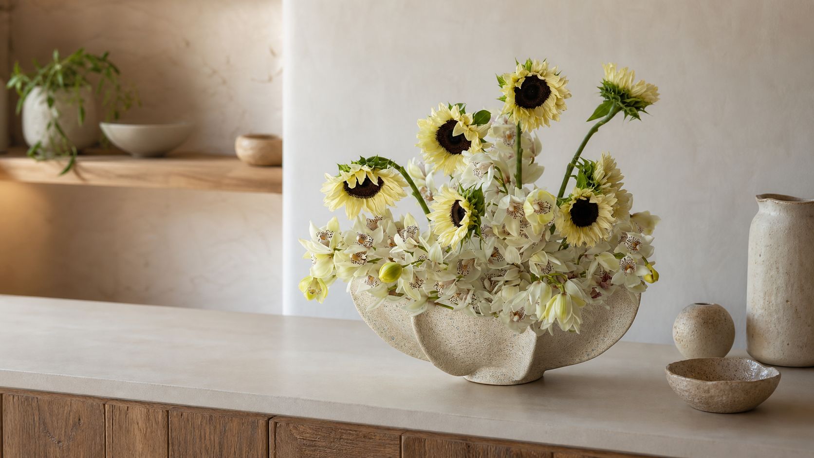 A sculptural handmade ceramic vessel arranged with pale flowers