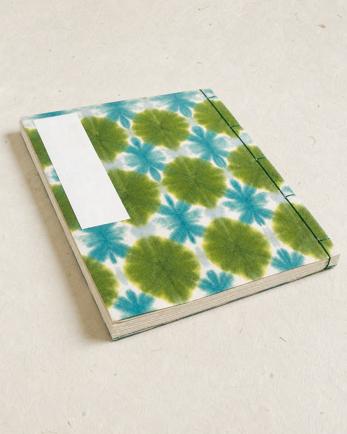 A hand-bound botanical paper journal on a warm handmade-paper surface