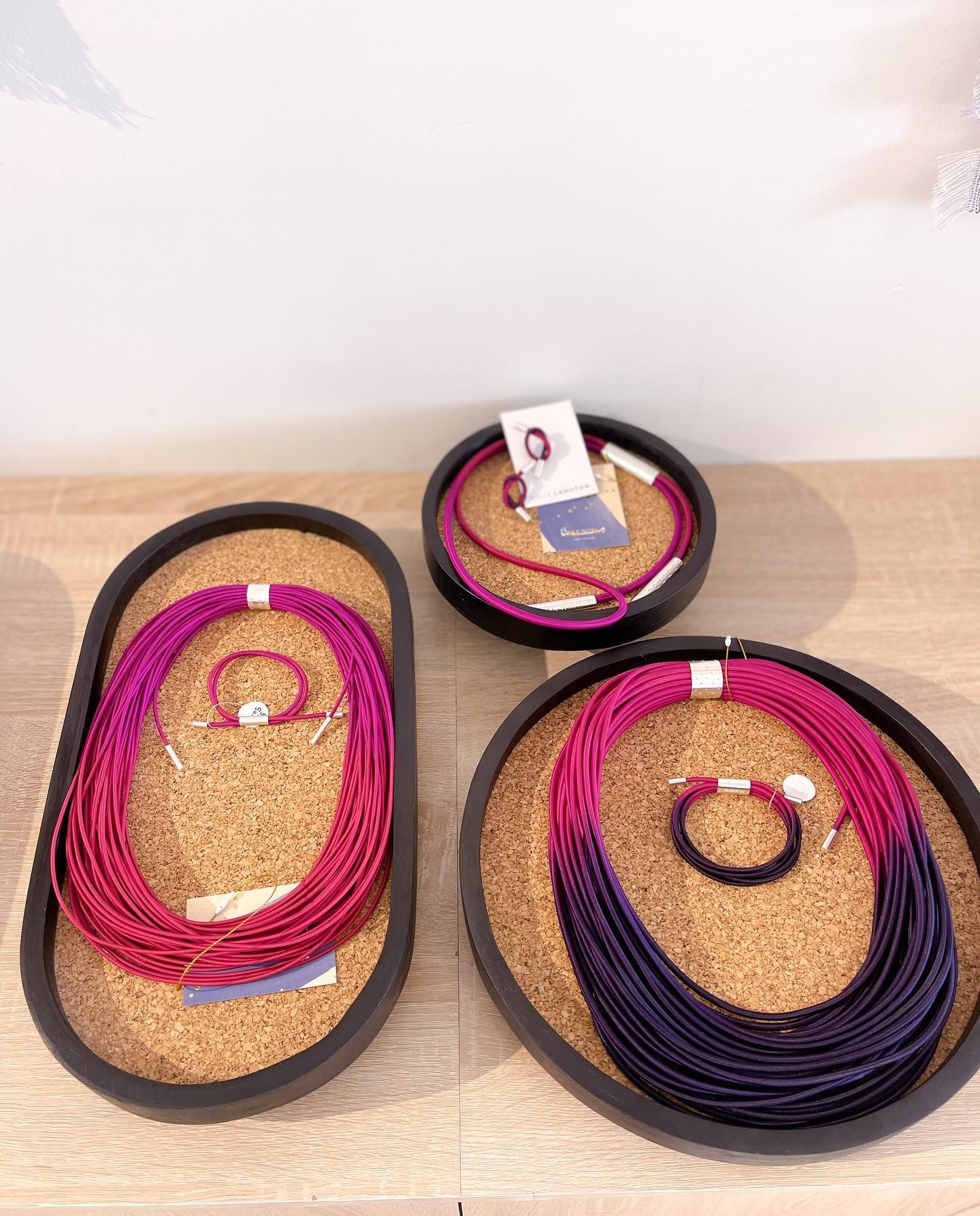 Magenta and violet statement jewellery arranged on cork display trays